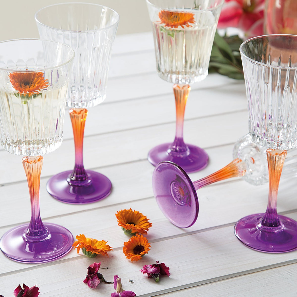 Tint & Form Vesper handblown crystal wine glasses with clear vertical-cut bowls and orange-to-purple gradient stems.